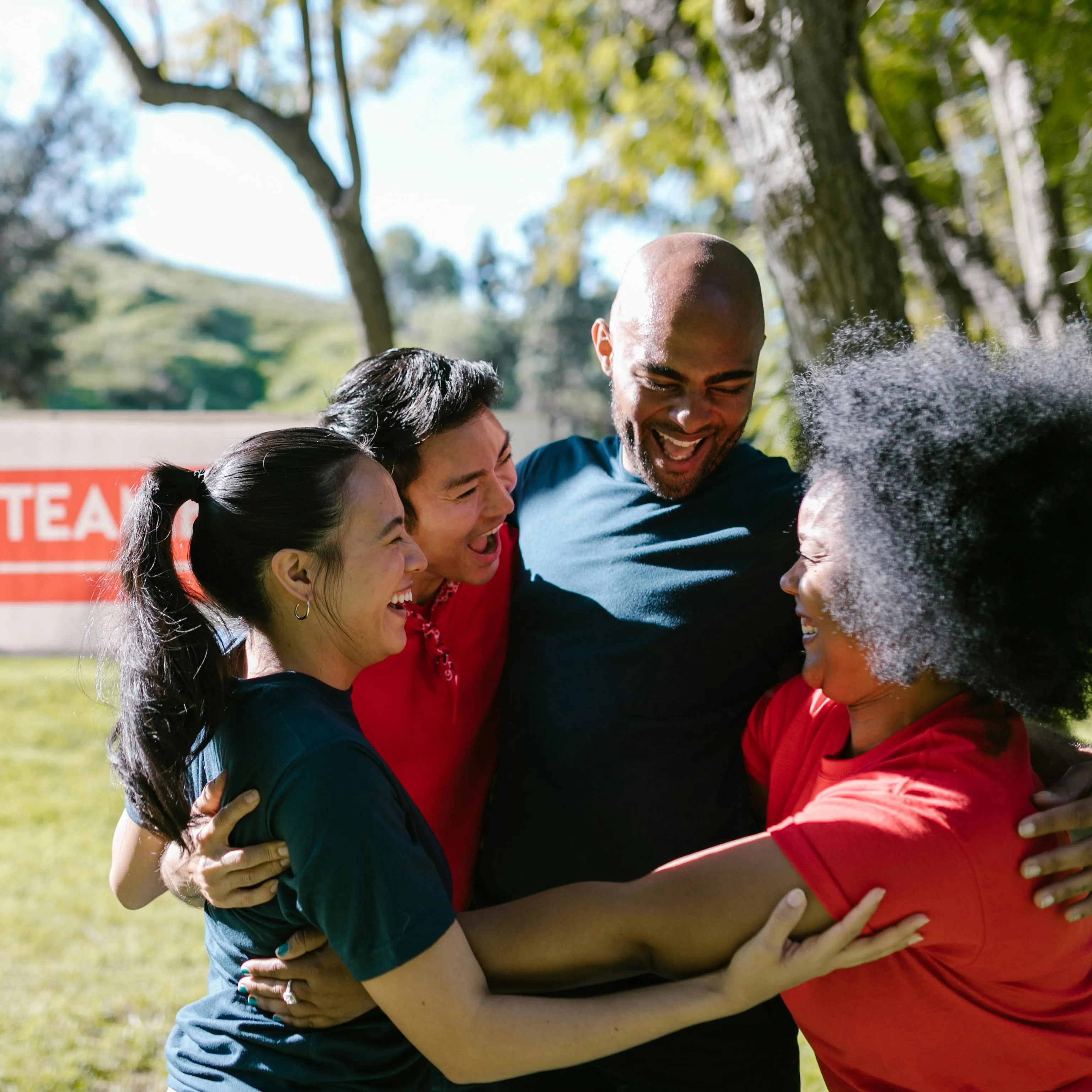 A team of four people hugging and smiling